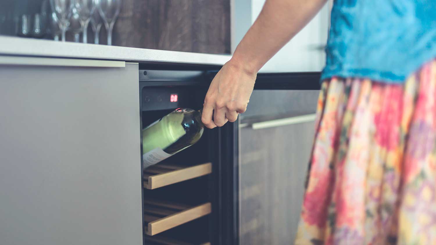 Woman taking wine bottle from the wine fridge