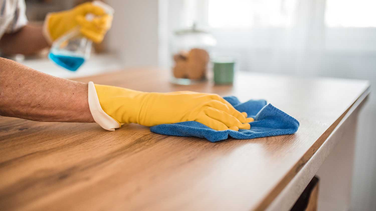 Person using a cloth to wipe a kitchen counter