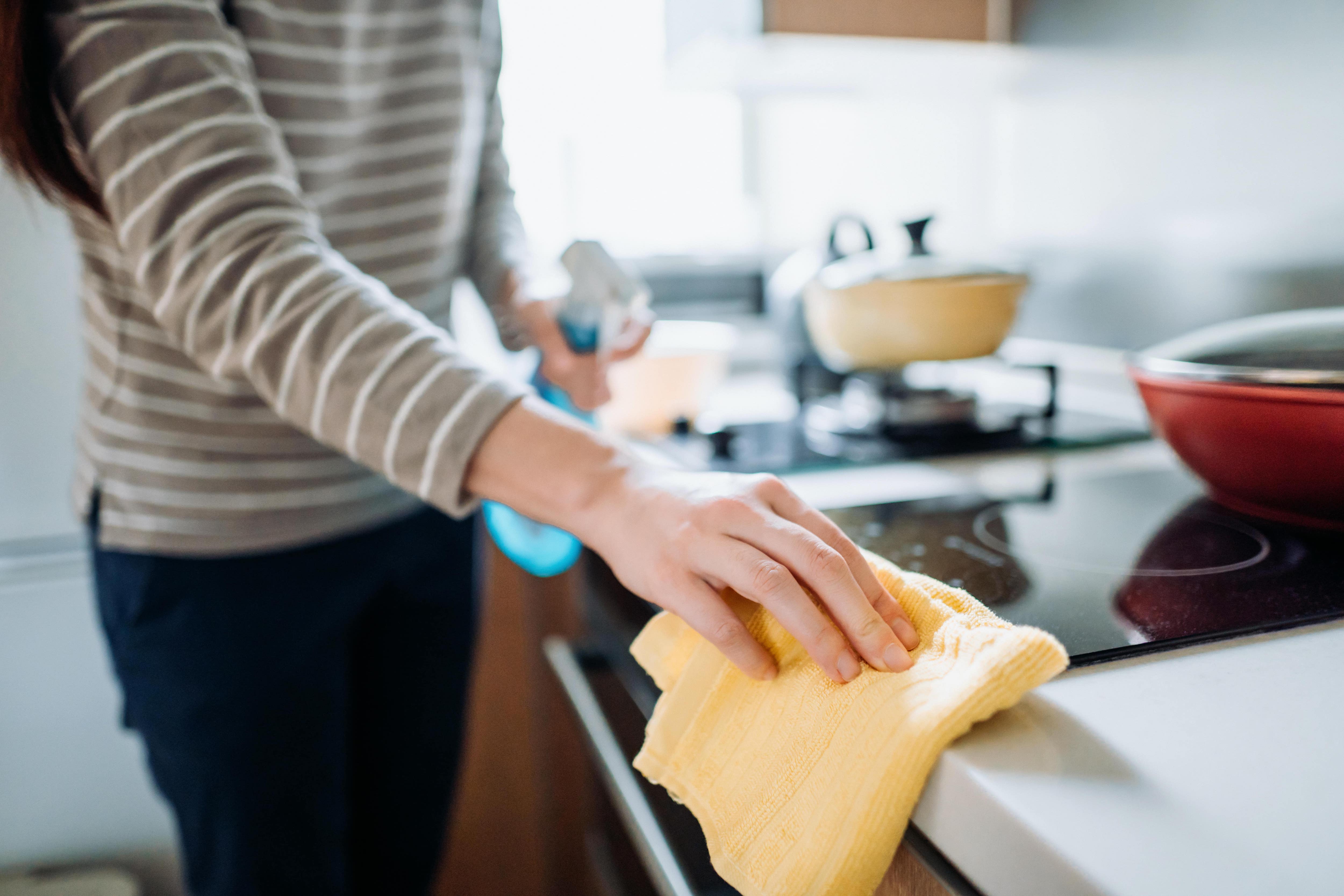 Woman cleaning countertops with cleaning spray and cloth