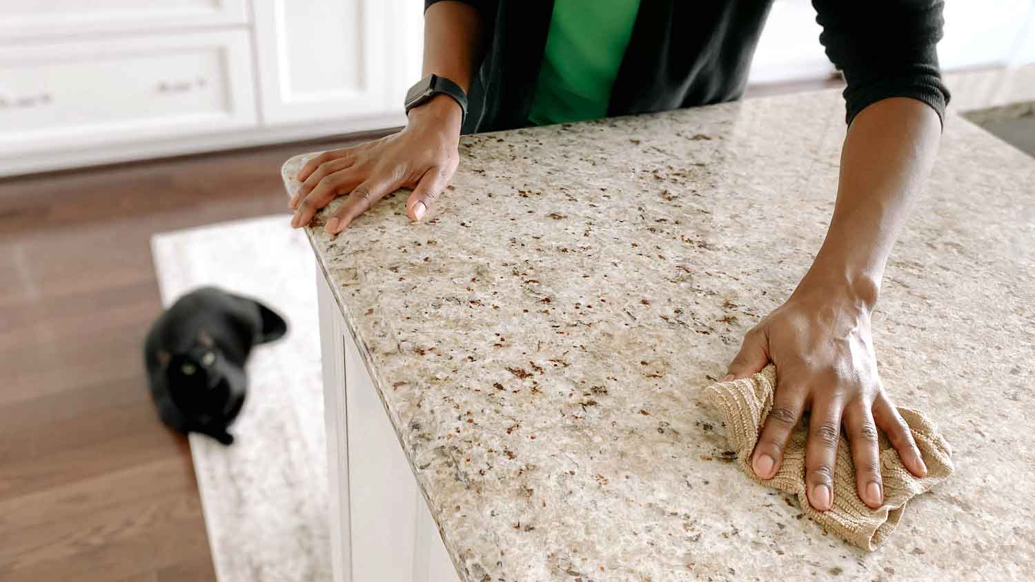 Cleaning granite kitchen counter with a cloth