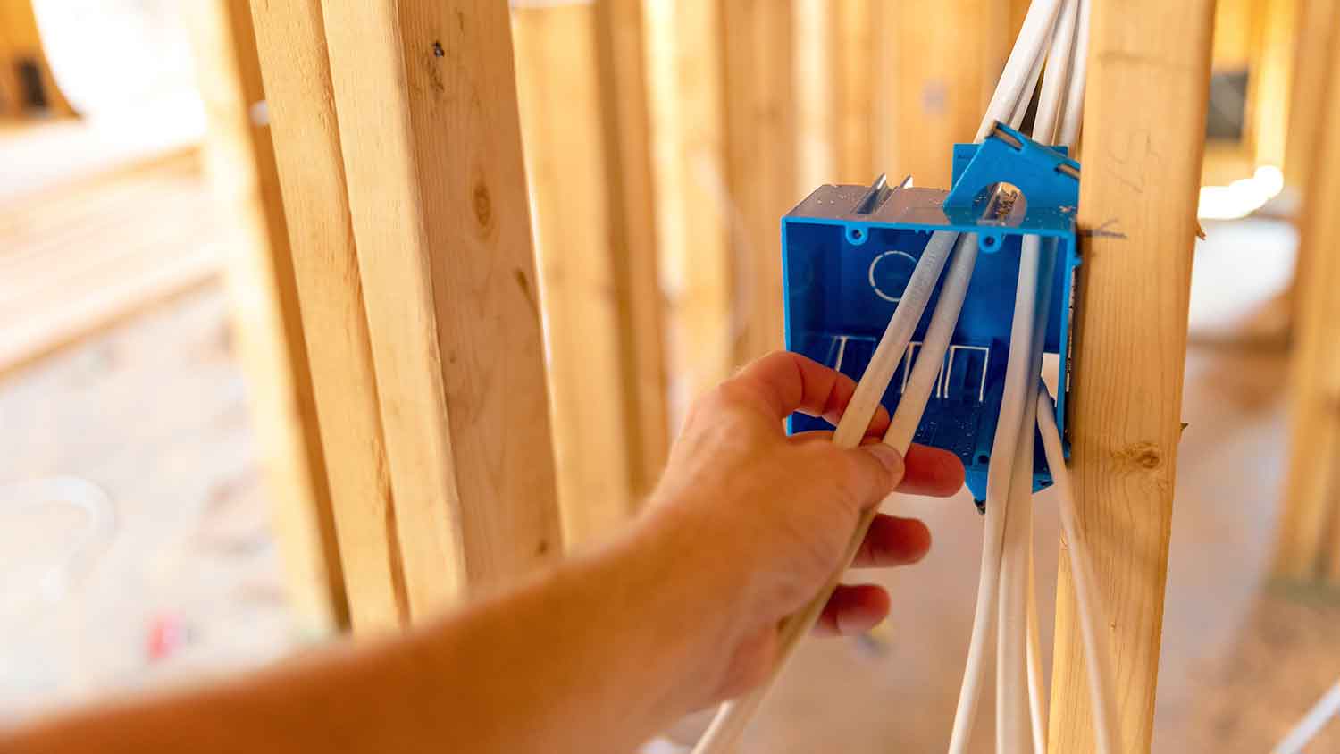 Electrician installing new outlet in a house under construction