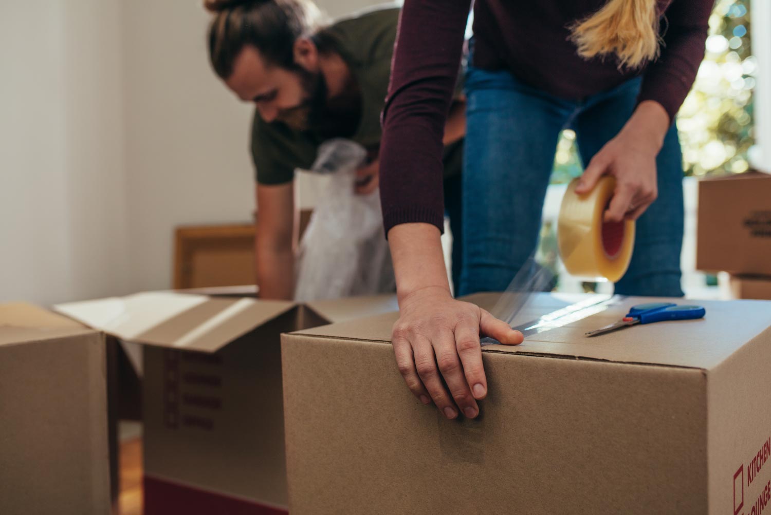 Woman applying adhesive tape on a packing box