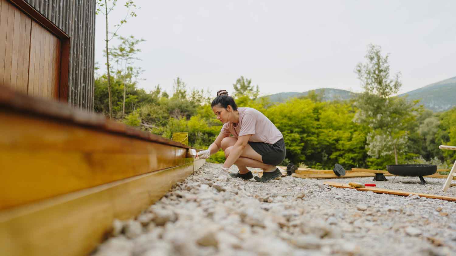 A woman applying oil with a brush on a wooden deck