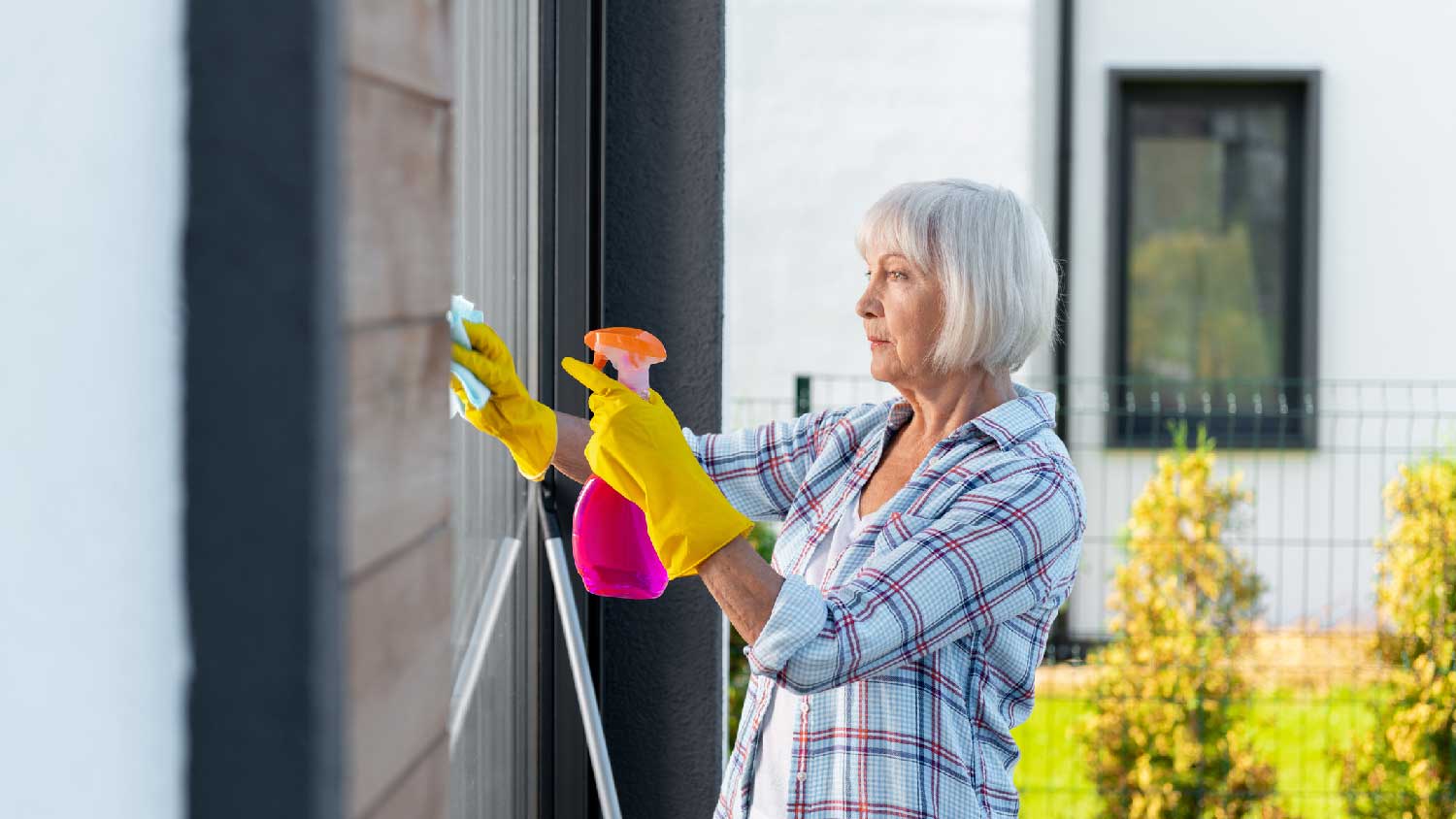 A woman applying a cleaning solution to an exterior window