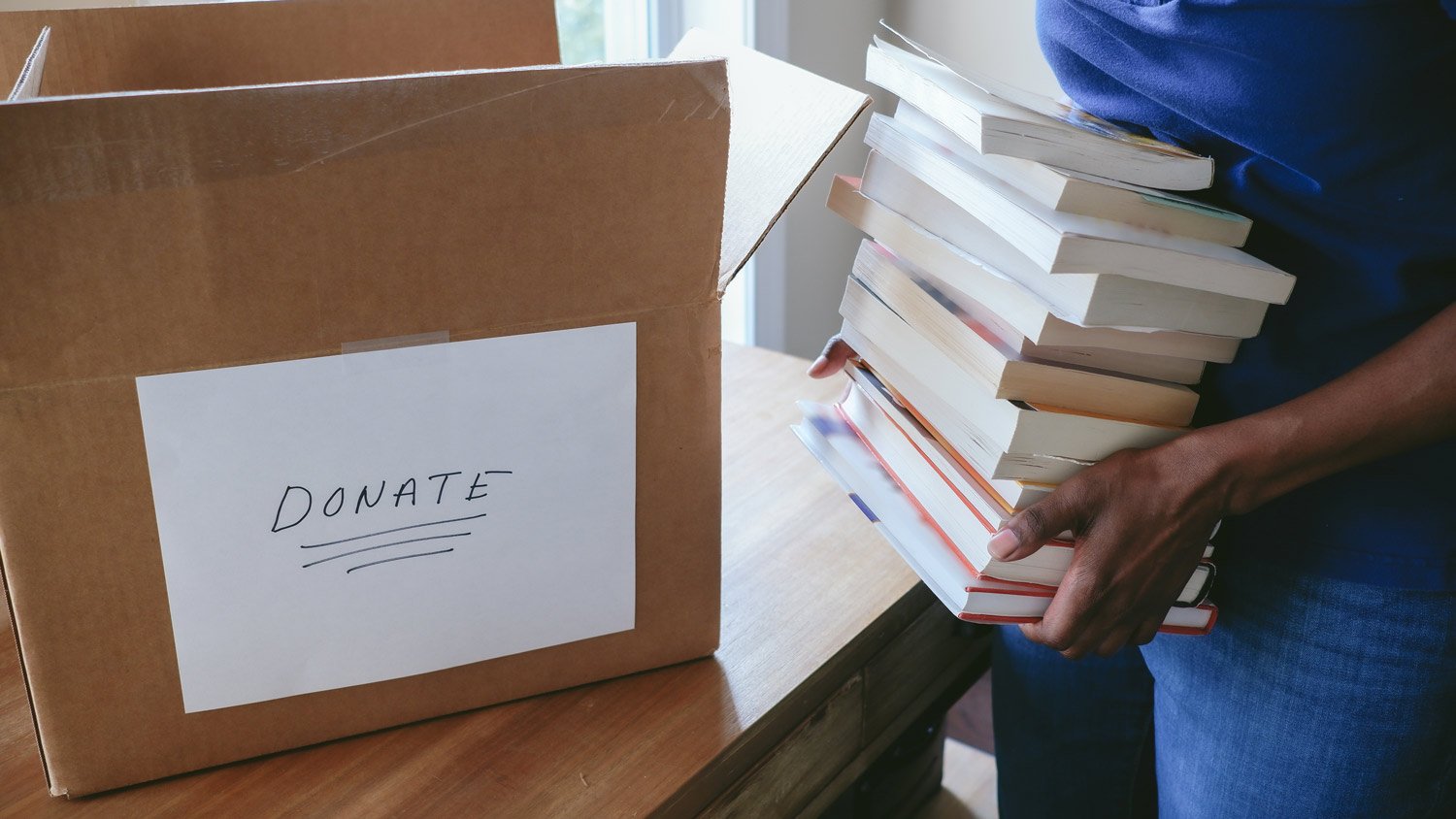 A woman puts books in a box for donation