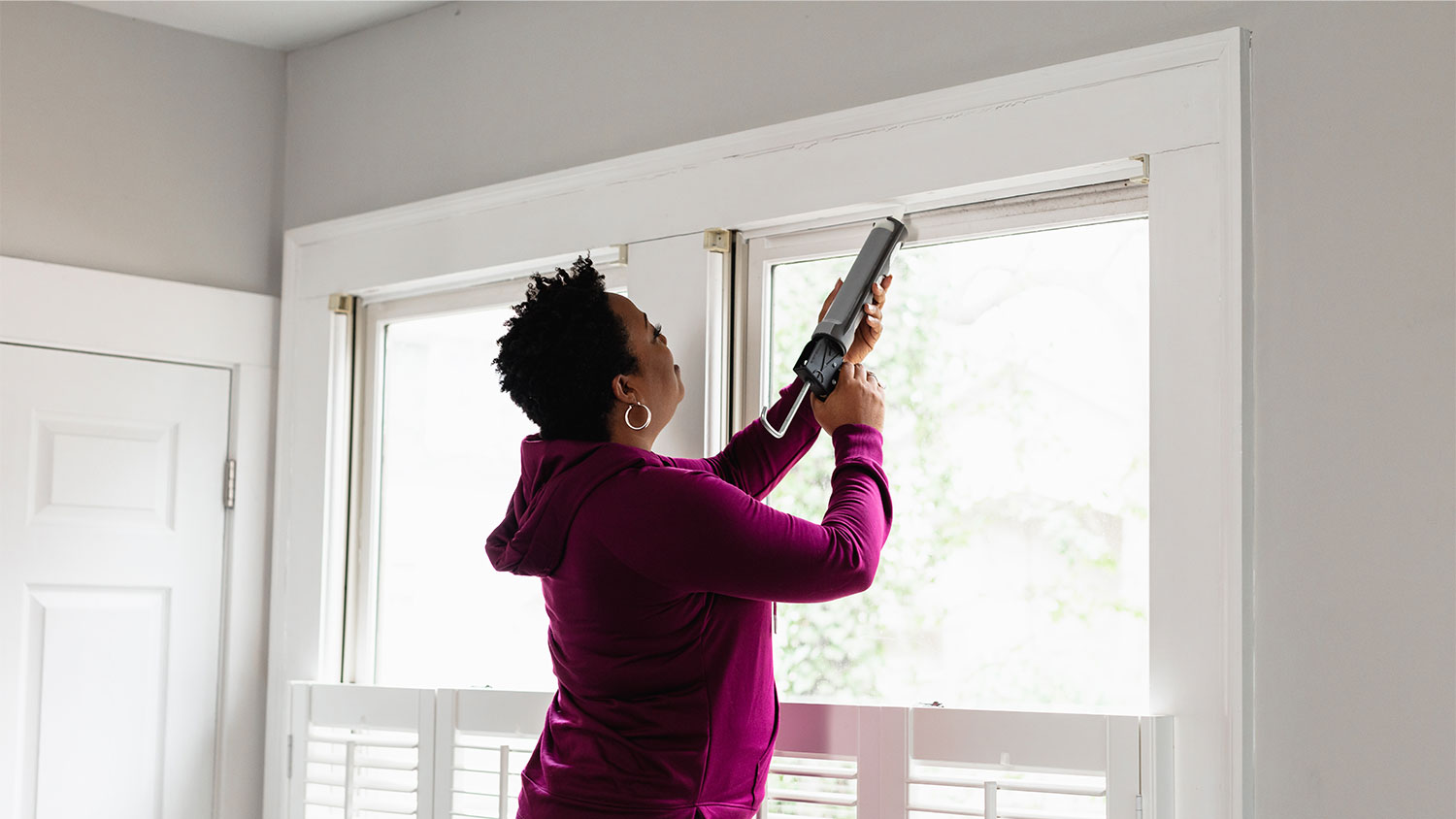 A woman caulks a window