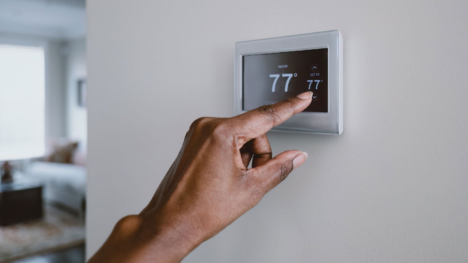 A woman changing the temperature via a thermostat