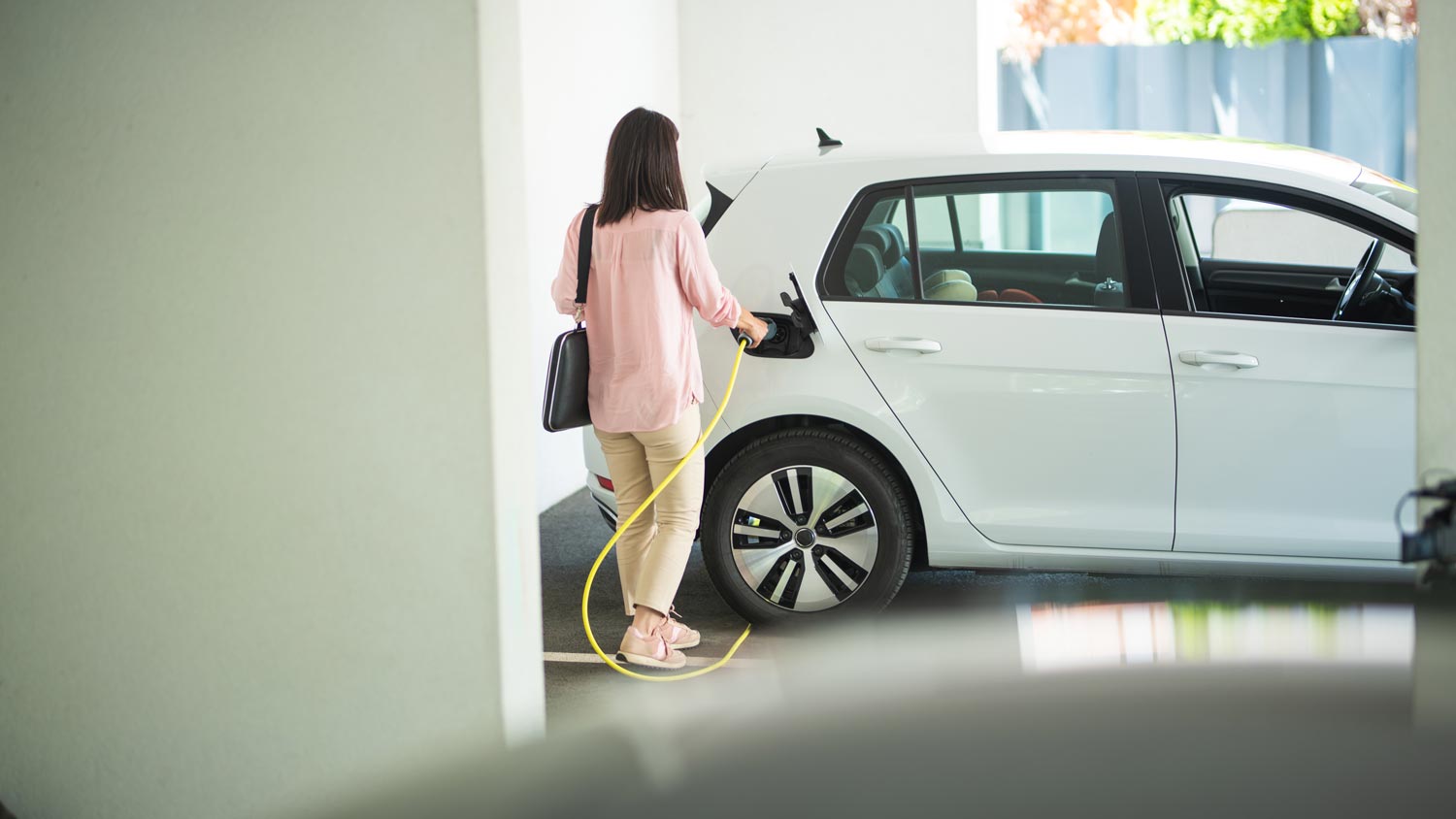 A woman charging her electric car in the garage