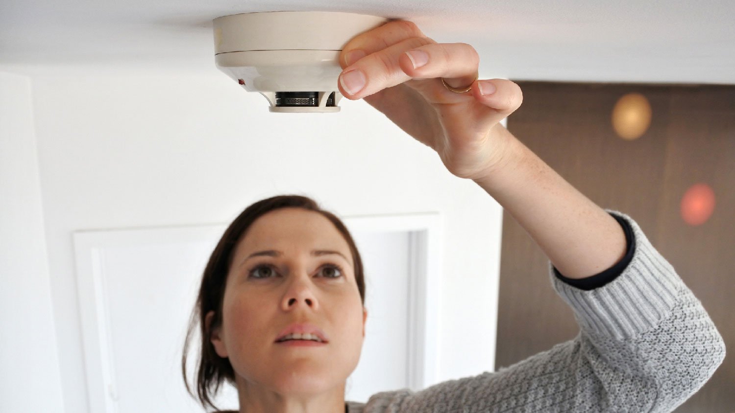 A woman checking the smoke alarm