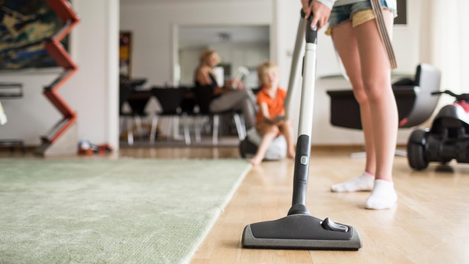 A woman cleaning floor with vacuum cleaner at home