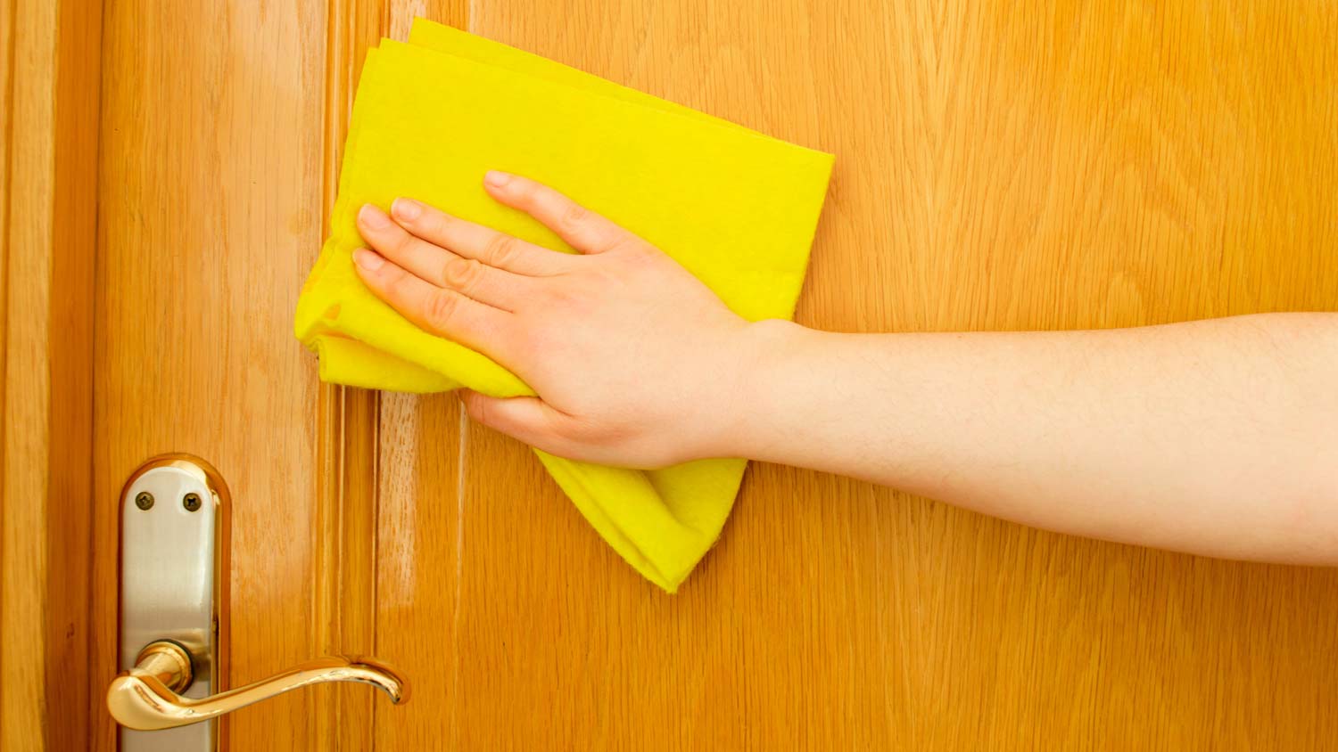 A woman cleaning the front door with a yellow cloth