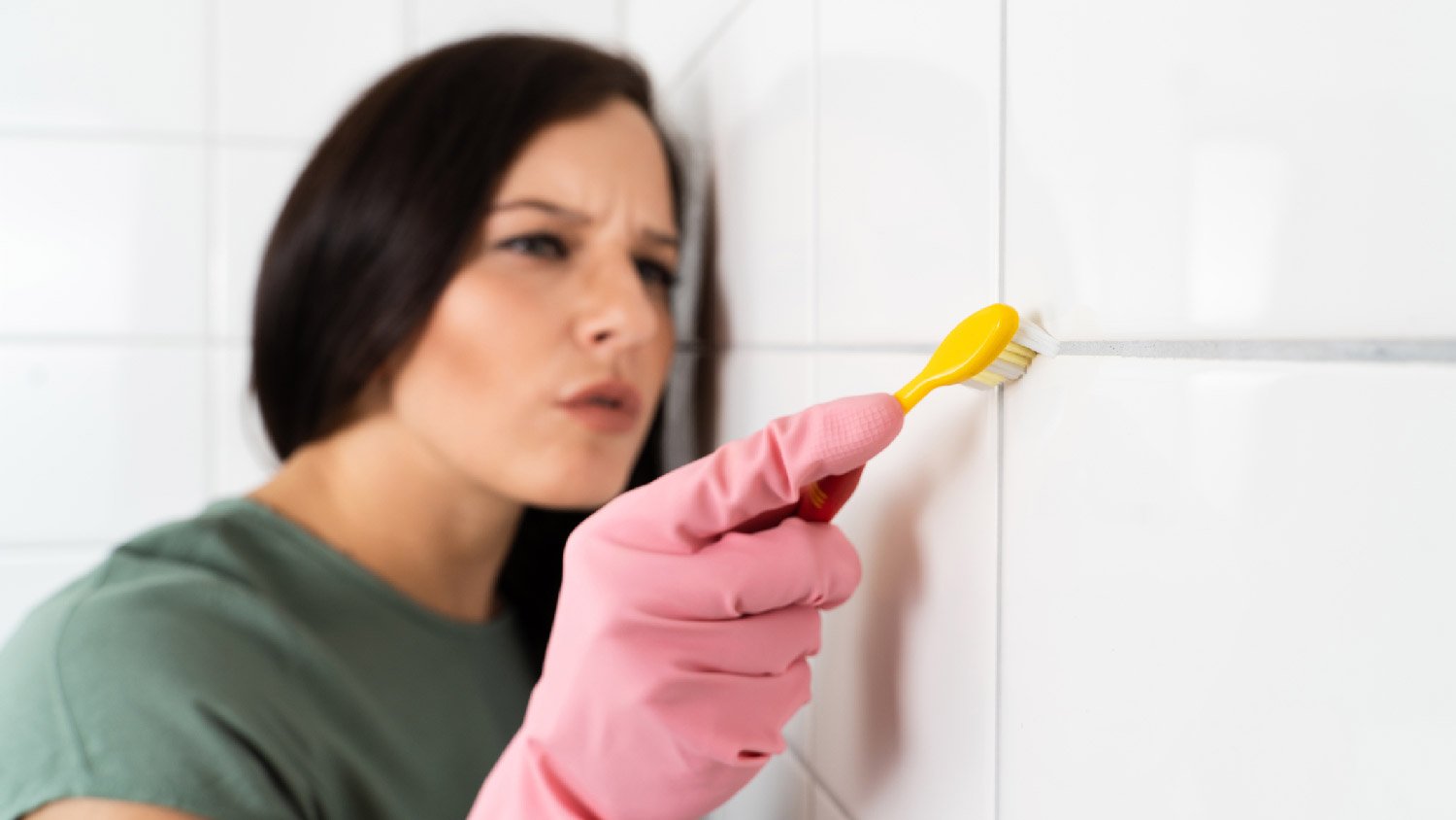 A woman cleaning the grout with a toothbrush 