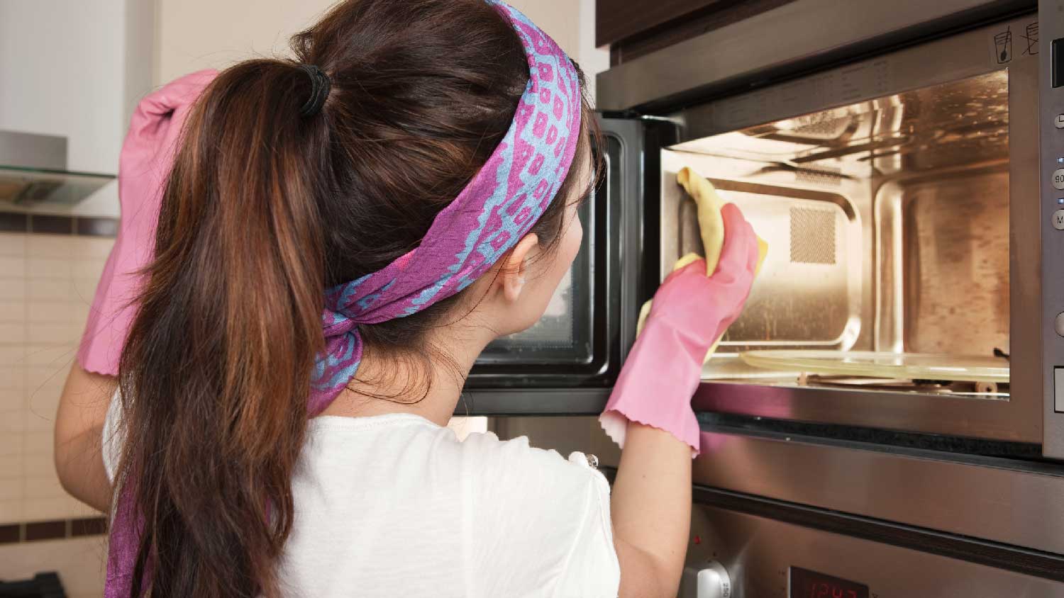 A woman cleaning the inside of a microwave