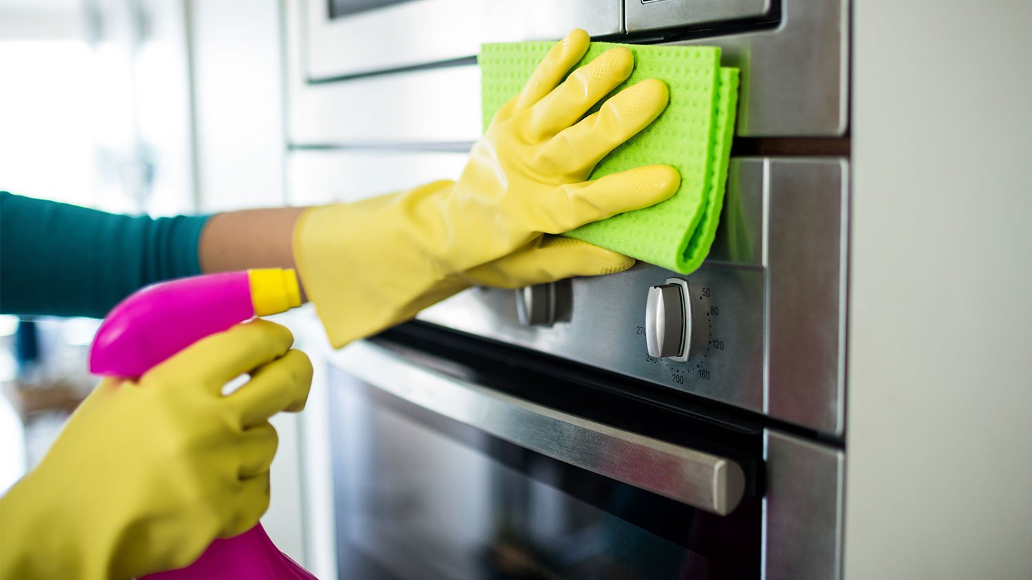 Woman using cleaning products to clean the oven