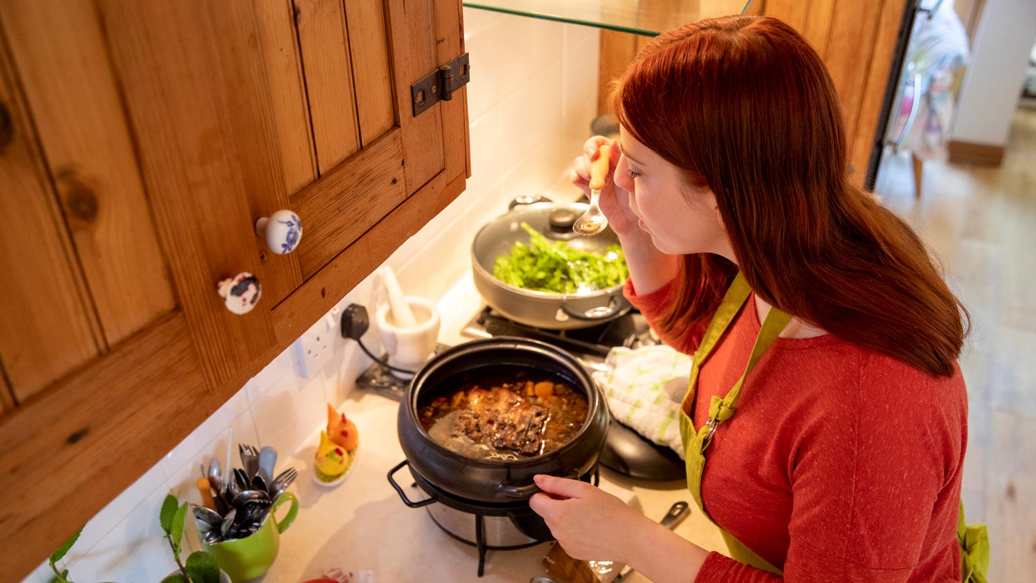 A woman tasting the casserole over the slow cooker