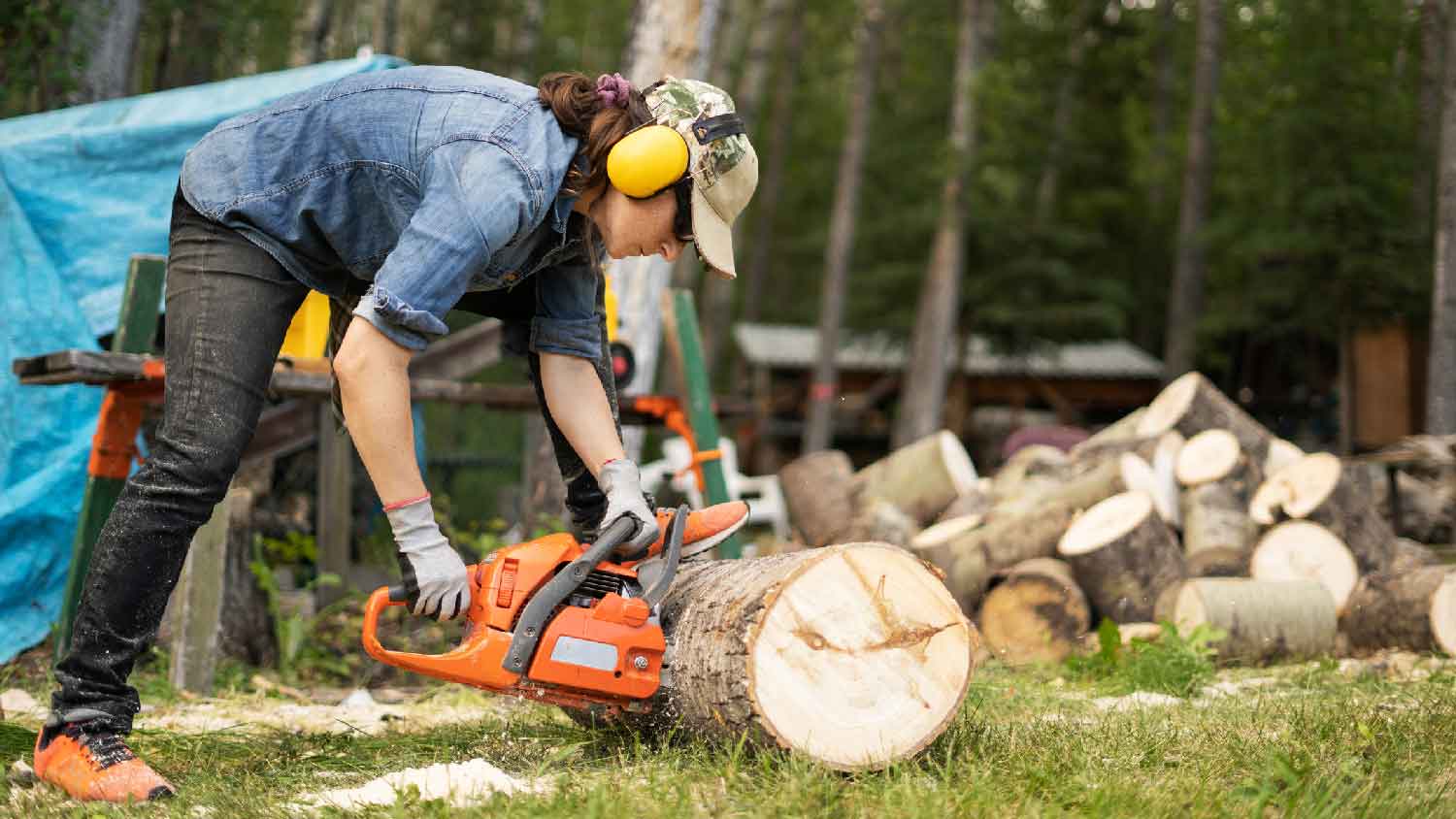 A woman cutting tree branches into firewood