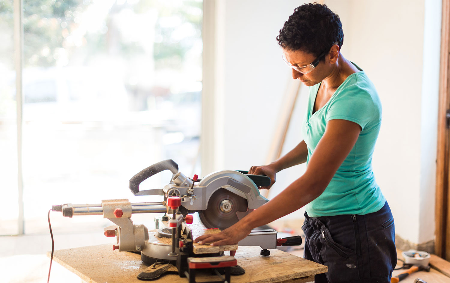 Woman cutting wooden board with electric saw