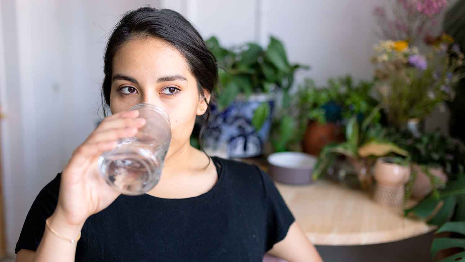 Young woman drinking water at home