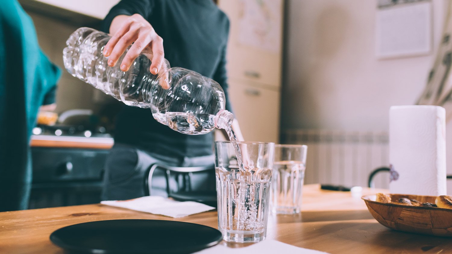  A woman filling up a glass with bottled water