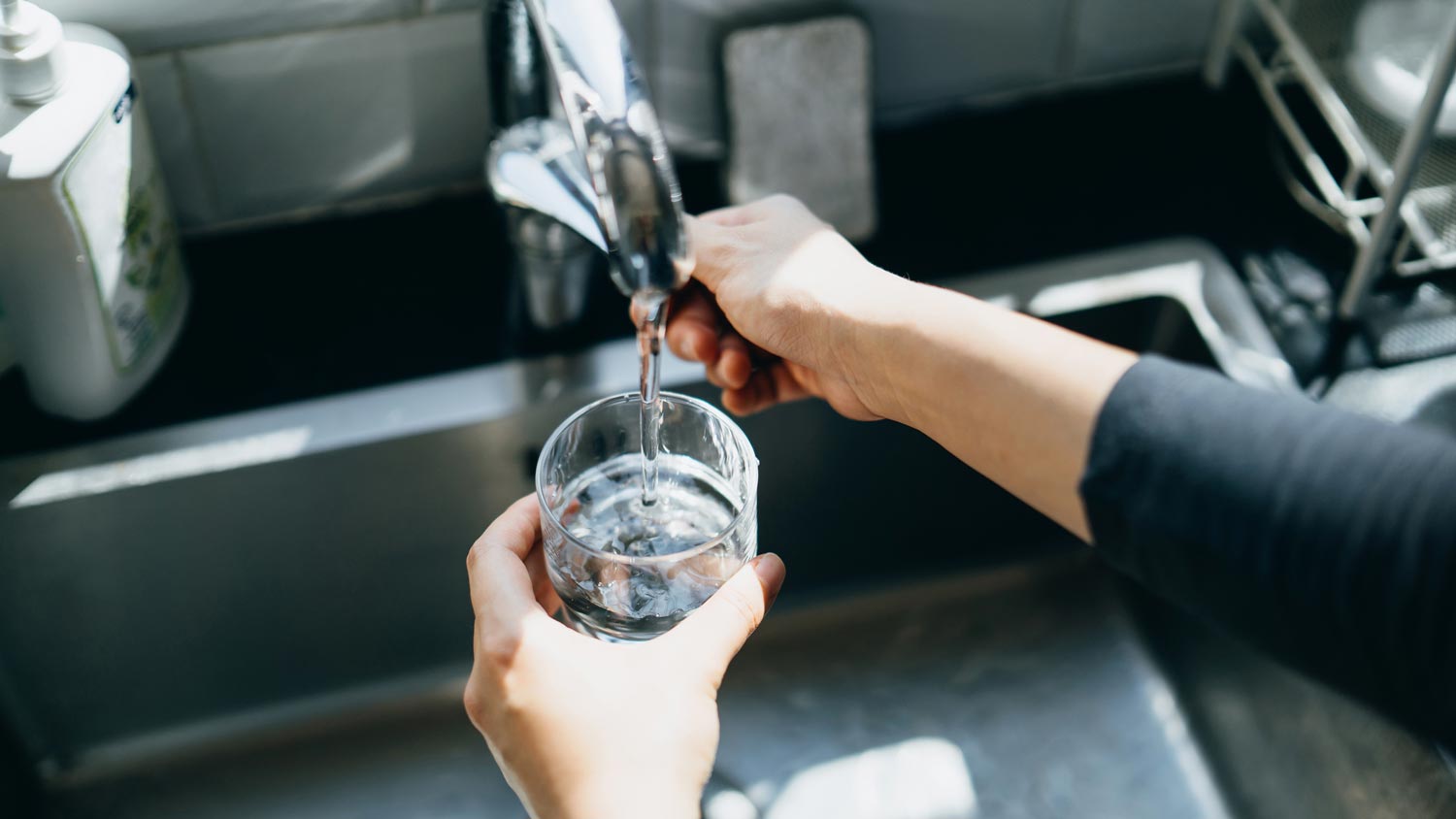 A woman filling a glass with tap water