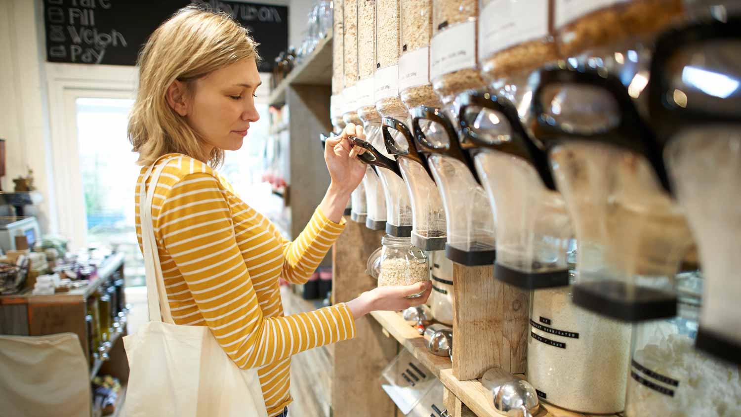 A woman filling a jar with oats in a grocery store