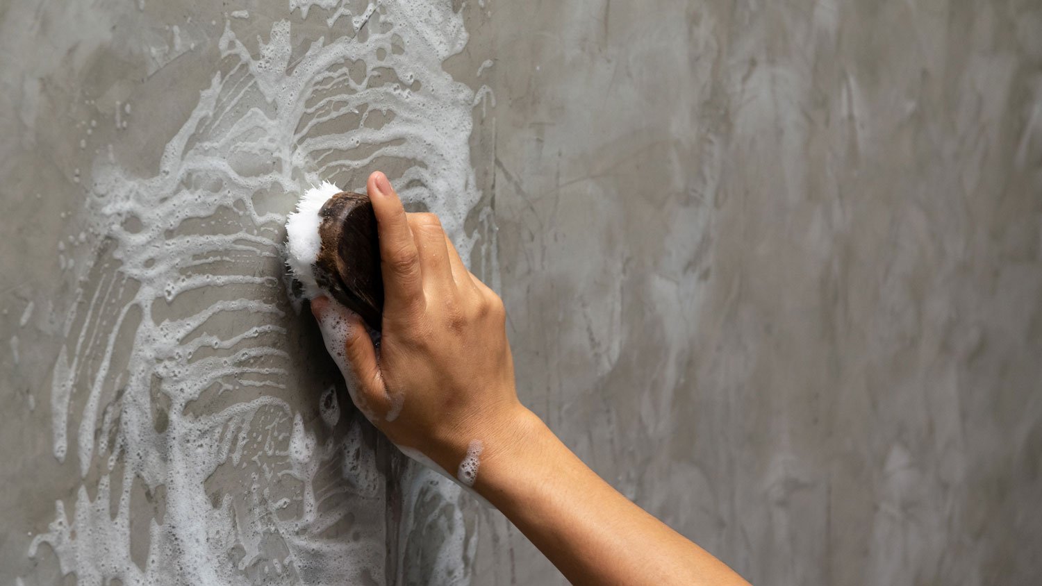 A woman handwashing a wall using a sponge