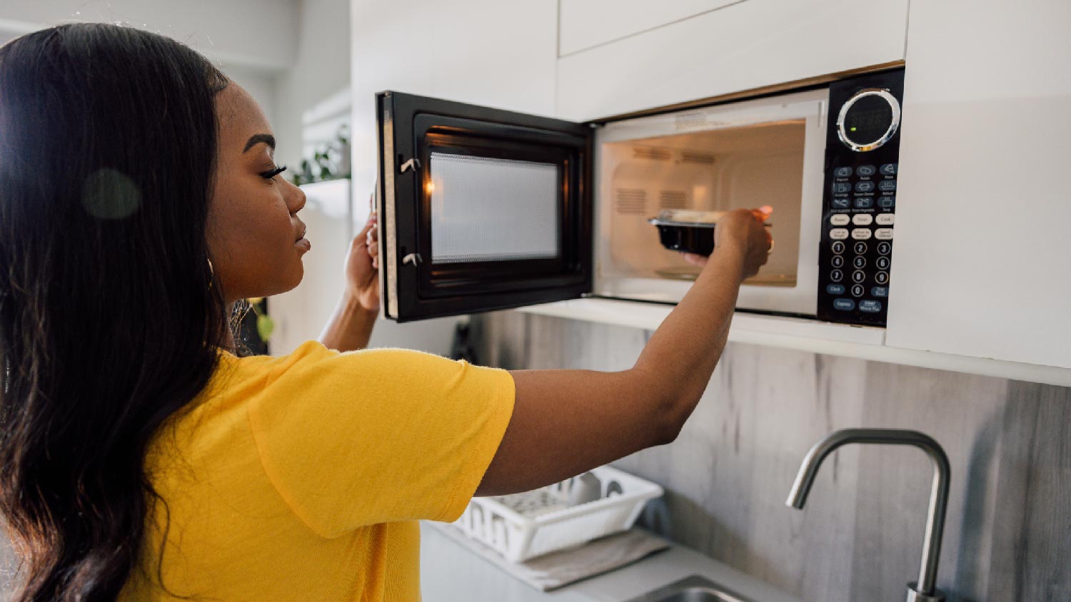 A woman heating food in the microwave