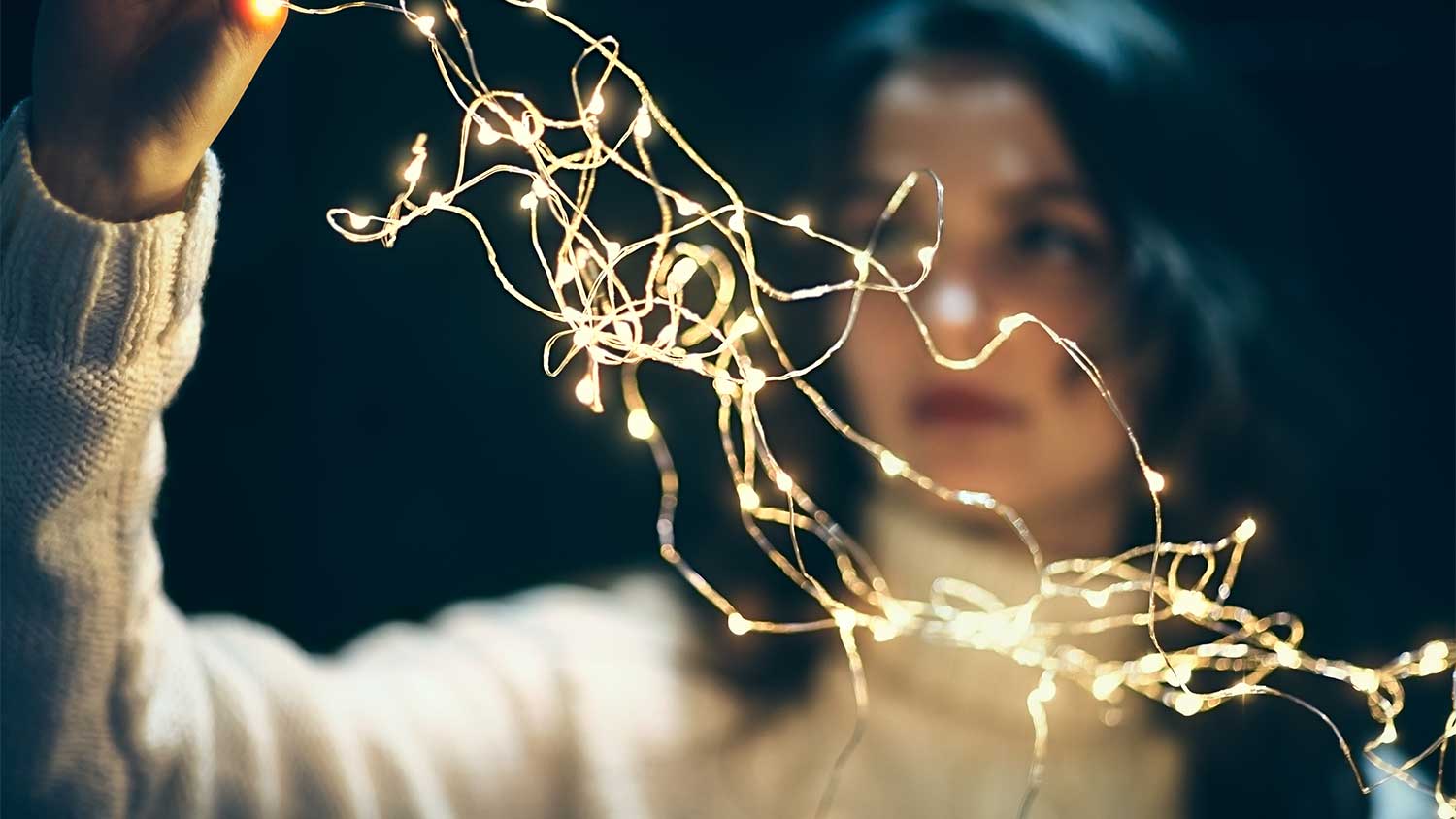 A woman holds christmas lights