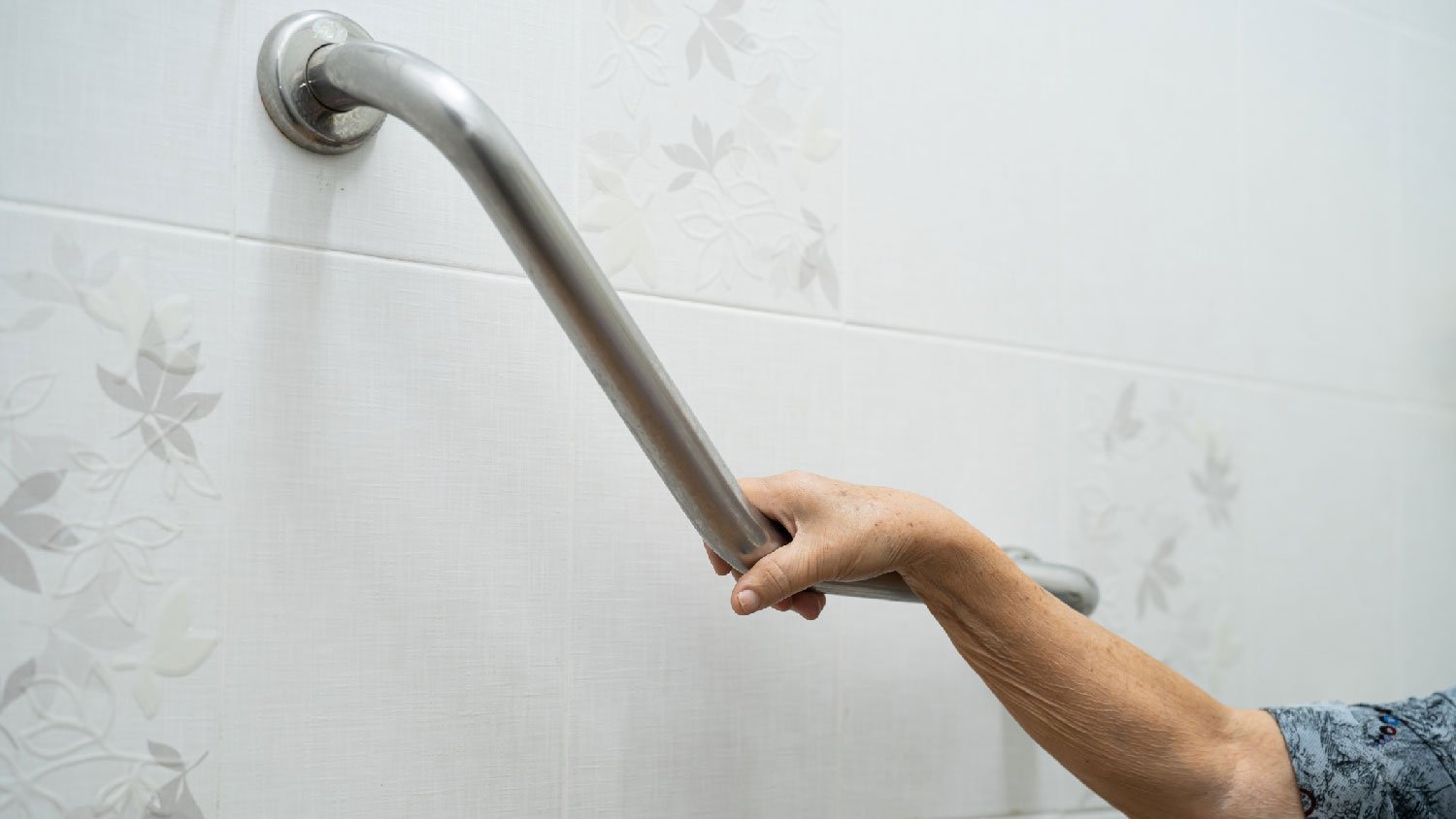 A senior woman holding a toilet grab bar