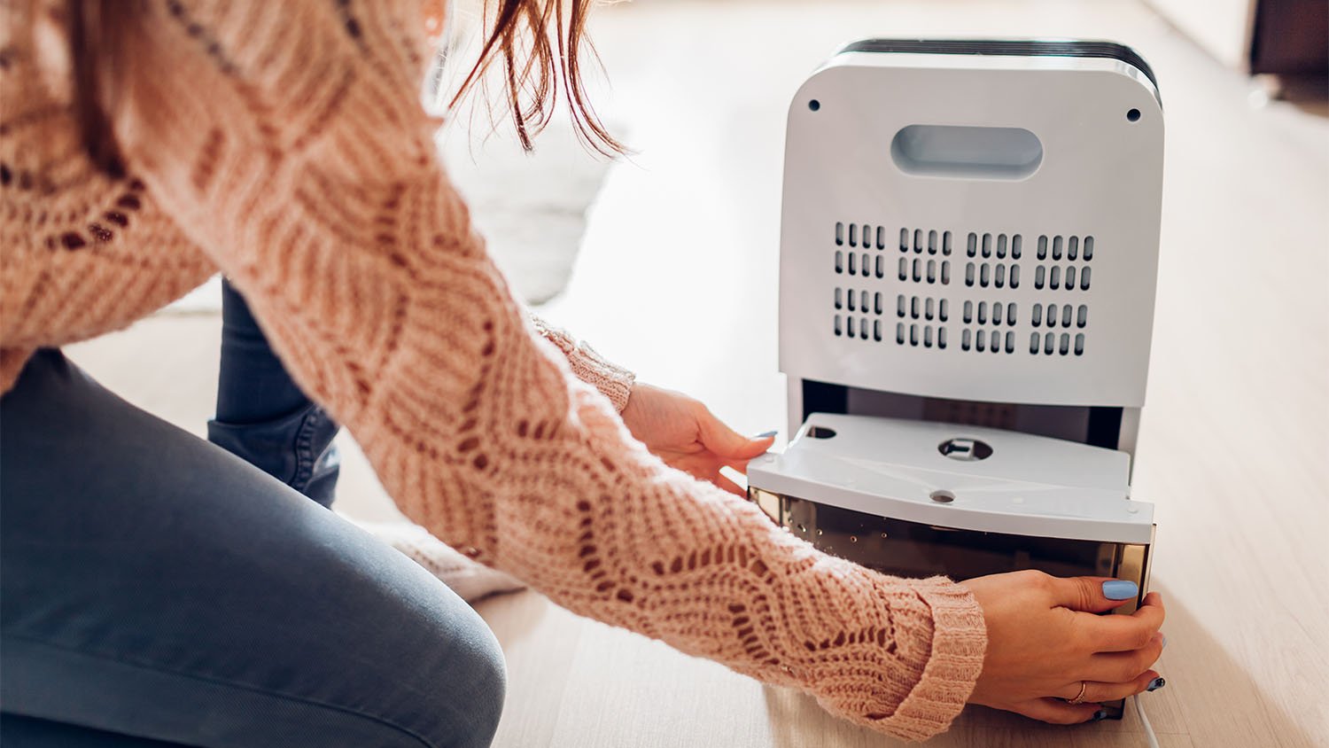 woman changing water in dehumidifier