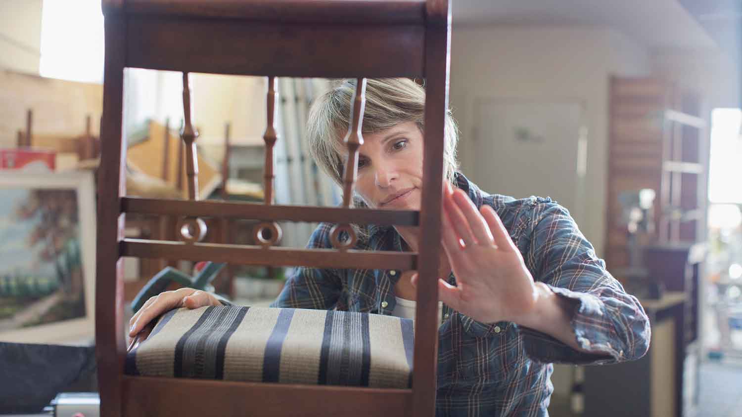 Woman in workshop inspecting wood chair