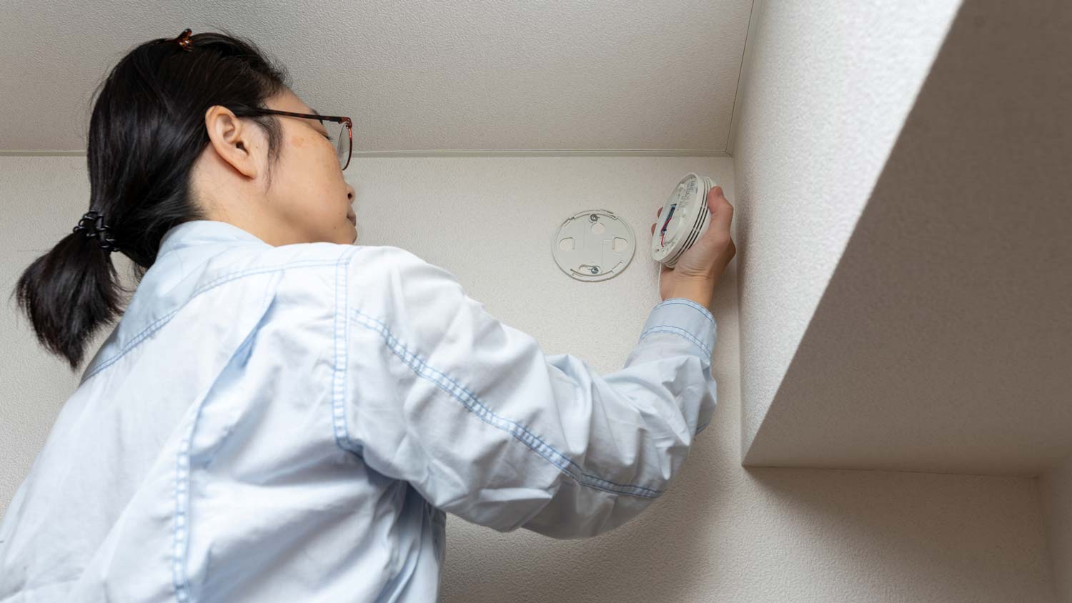 A woman inspecting smoke alarm settings