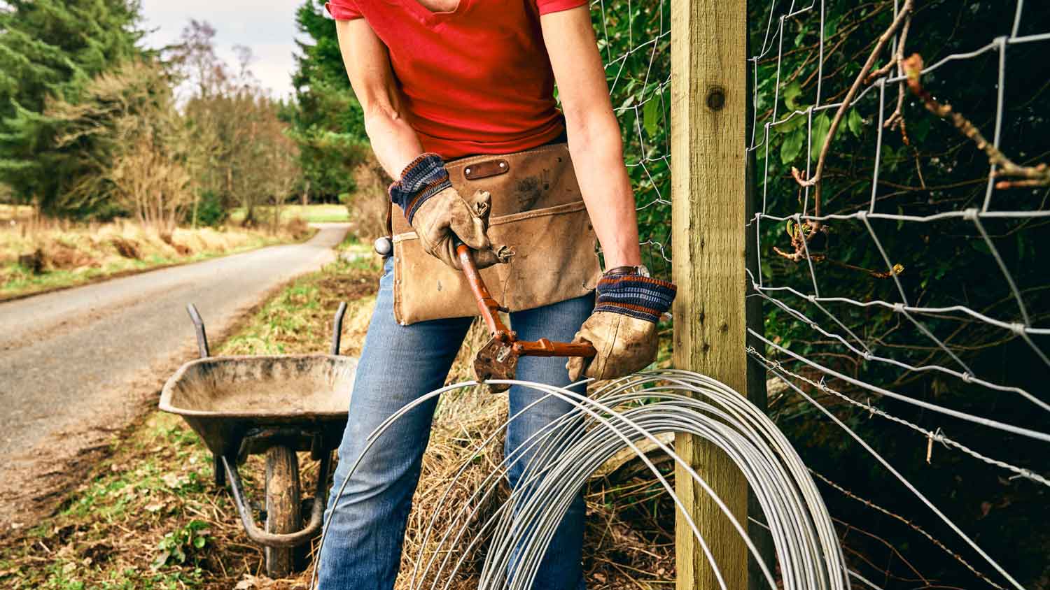 A woman installing a chain link fence
