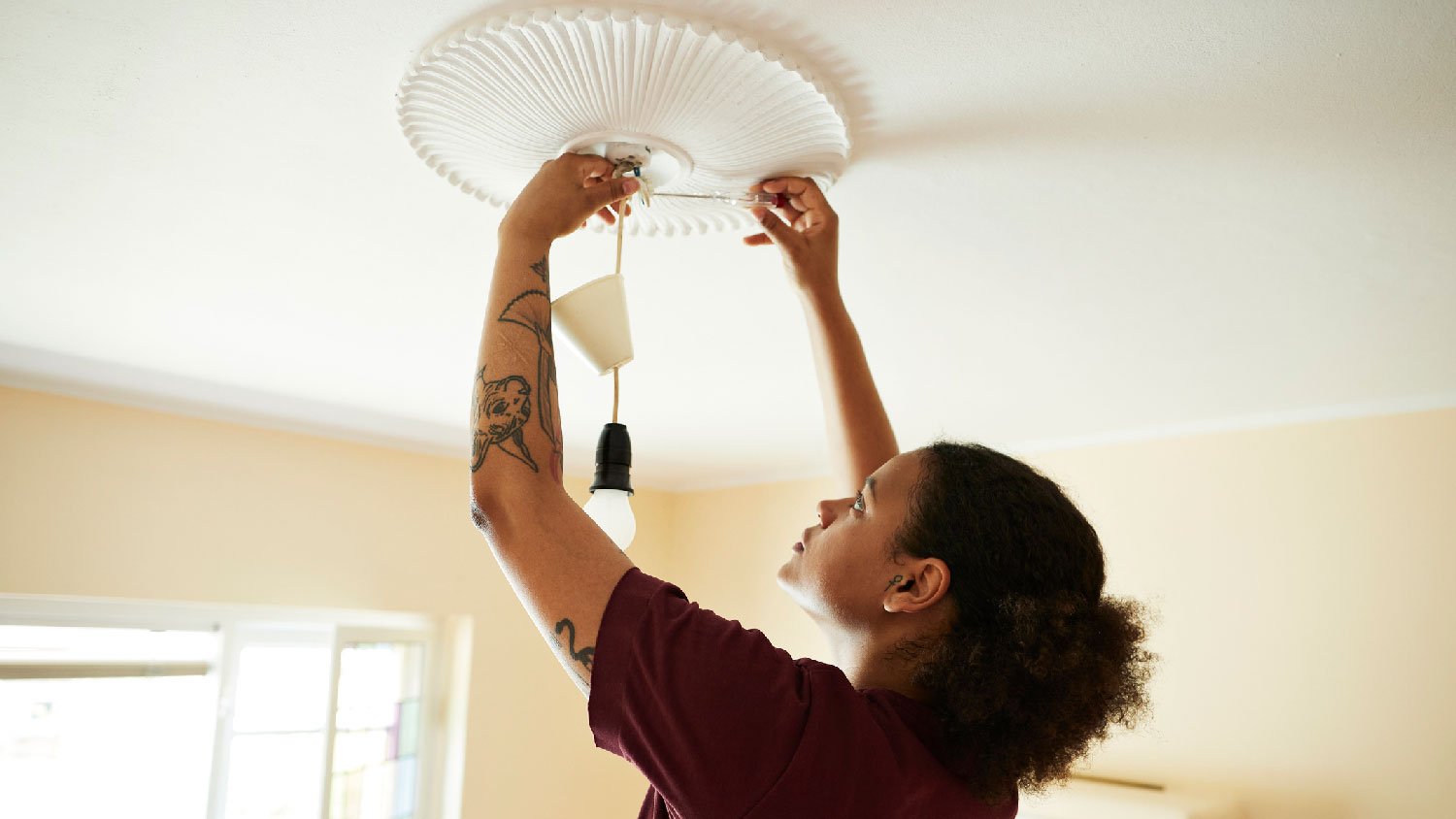 A woman installing a new pendant light 