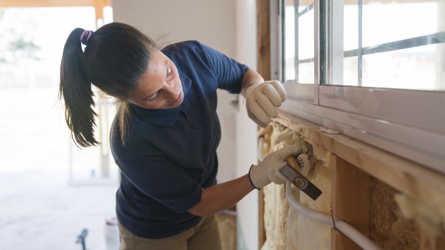 A woman adding insulation to a wall