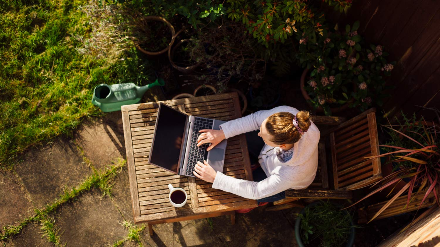 A woman working with her laptop in a garden