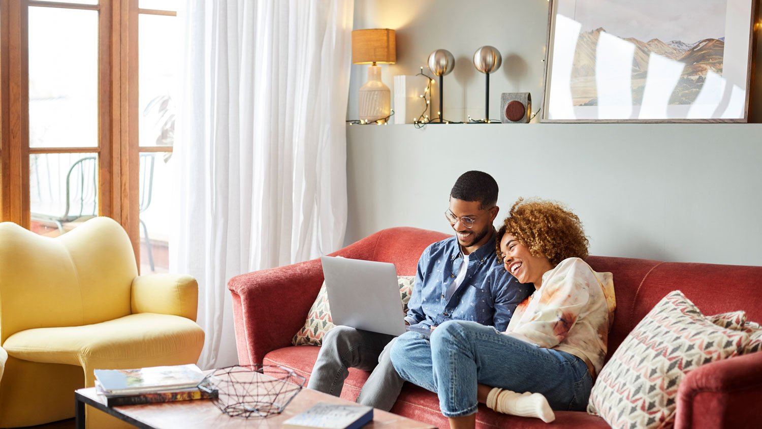 A woman leaning on a man using a laptop in their living room