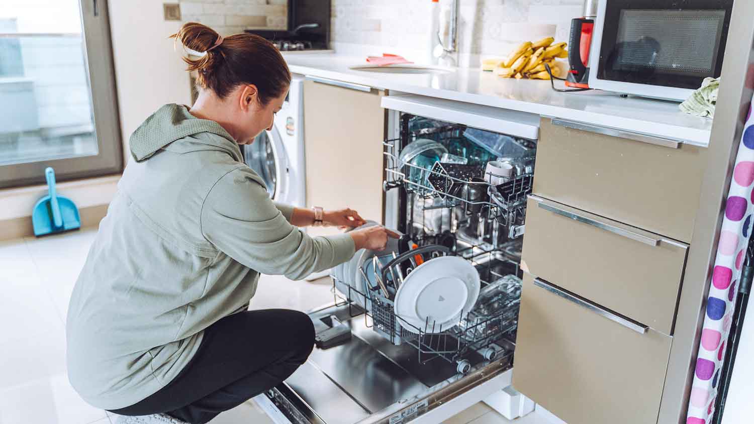 Woman in the kitchen loading dishwasher