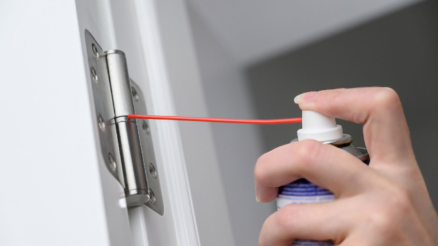 Close-up of a woman lubricating door hinges