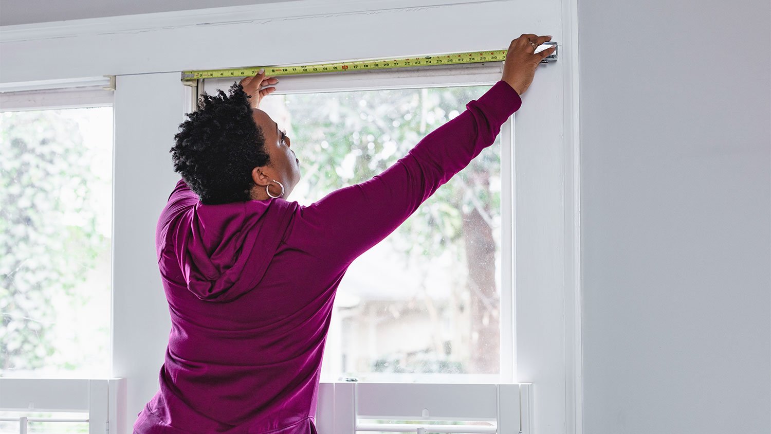 woman measuring width of window