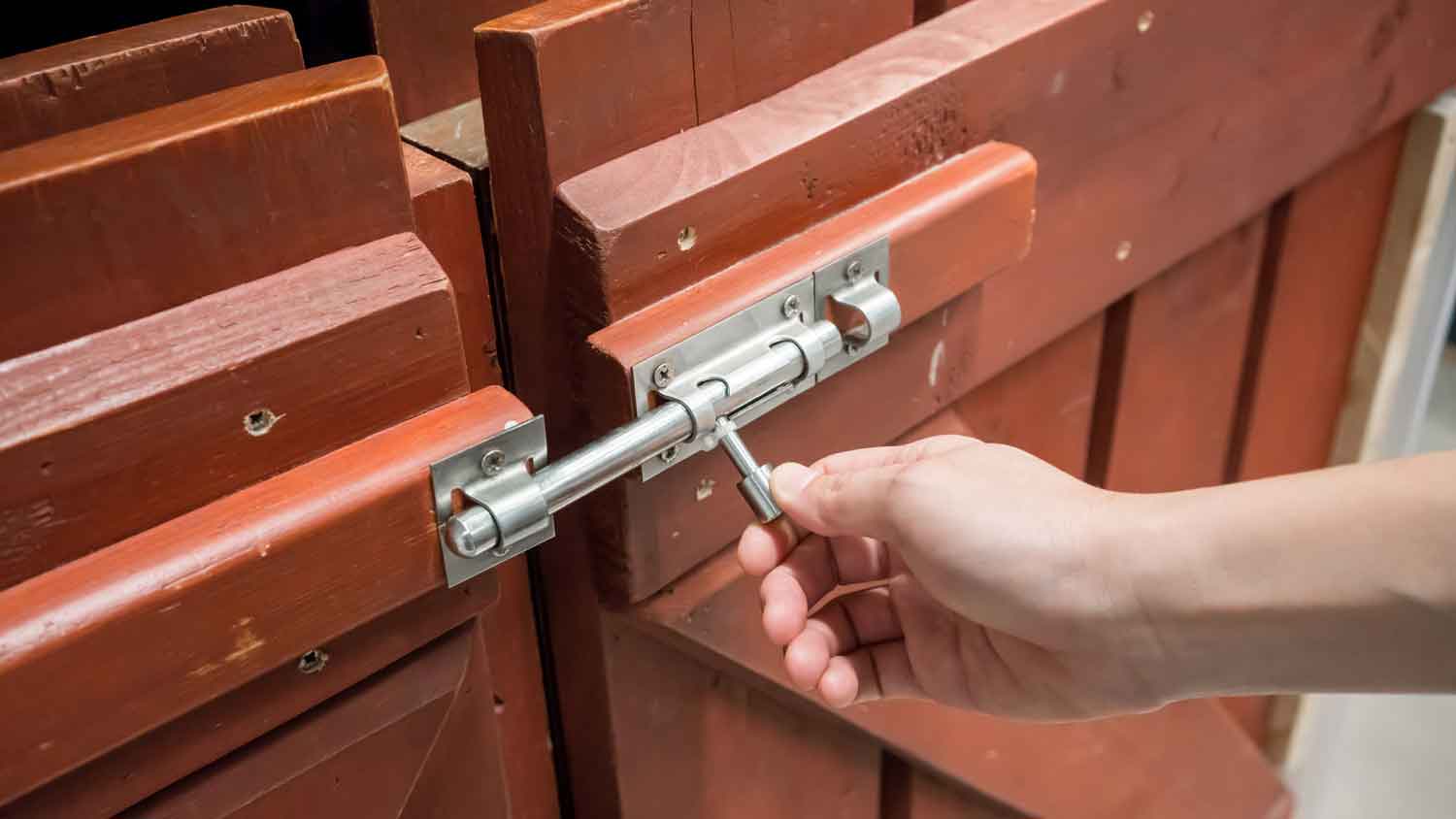 A woman opening the latch of a gate