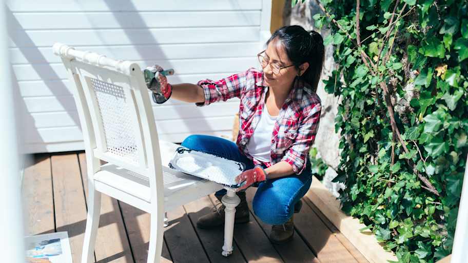 Woman painting a white chair on the patio