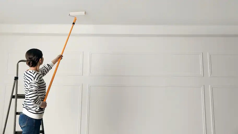 woman painting ceiling white