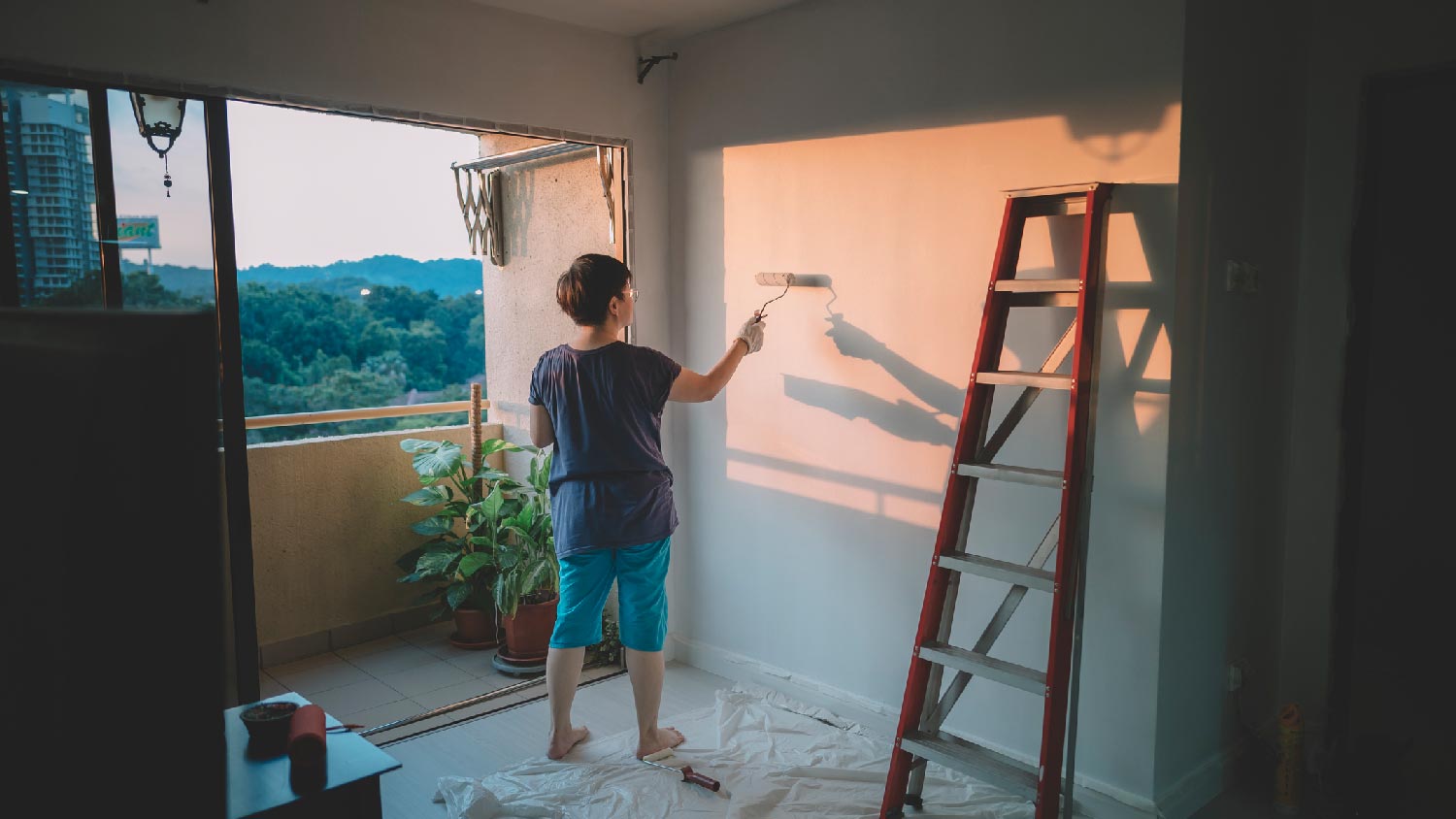 A woman painting the living room with a roller 