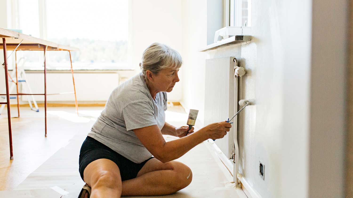 Woman sitting on the floor painting a wall