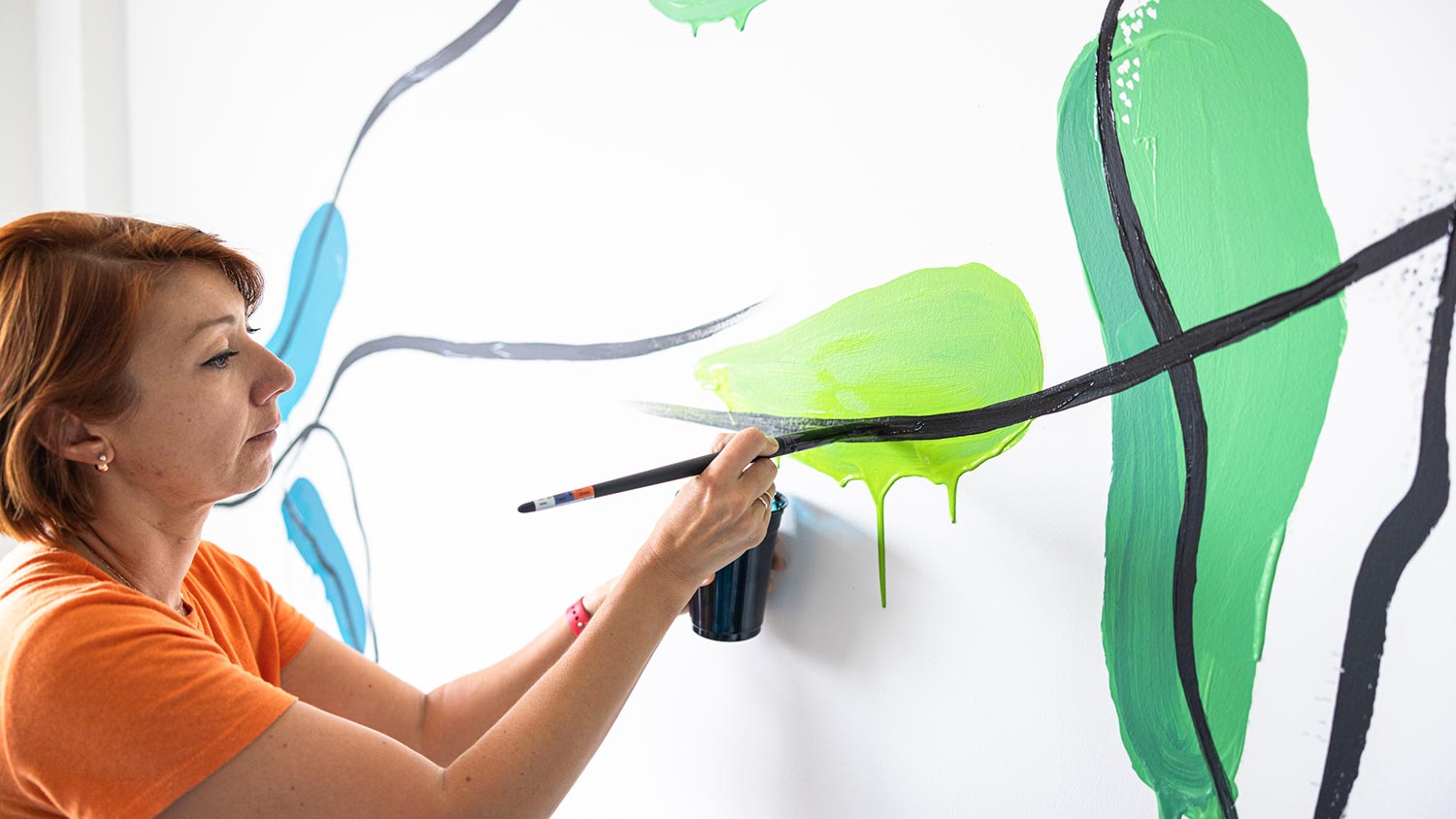 A woman painting a mural on a wall