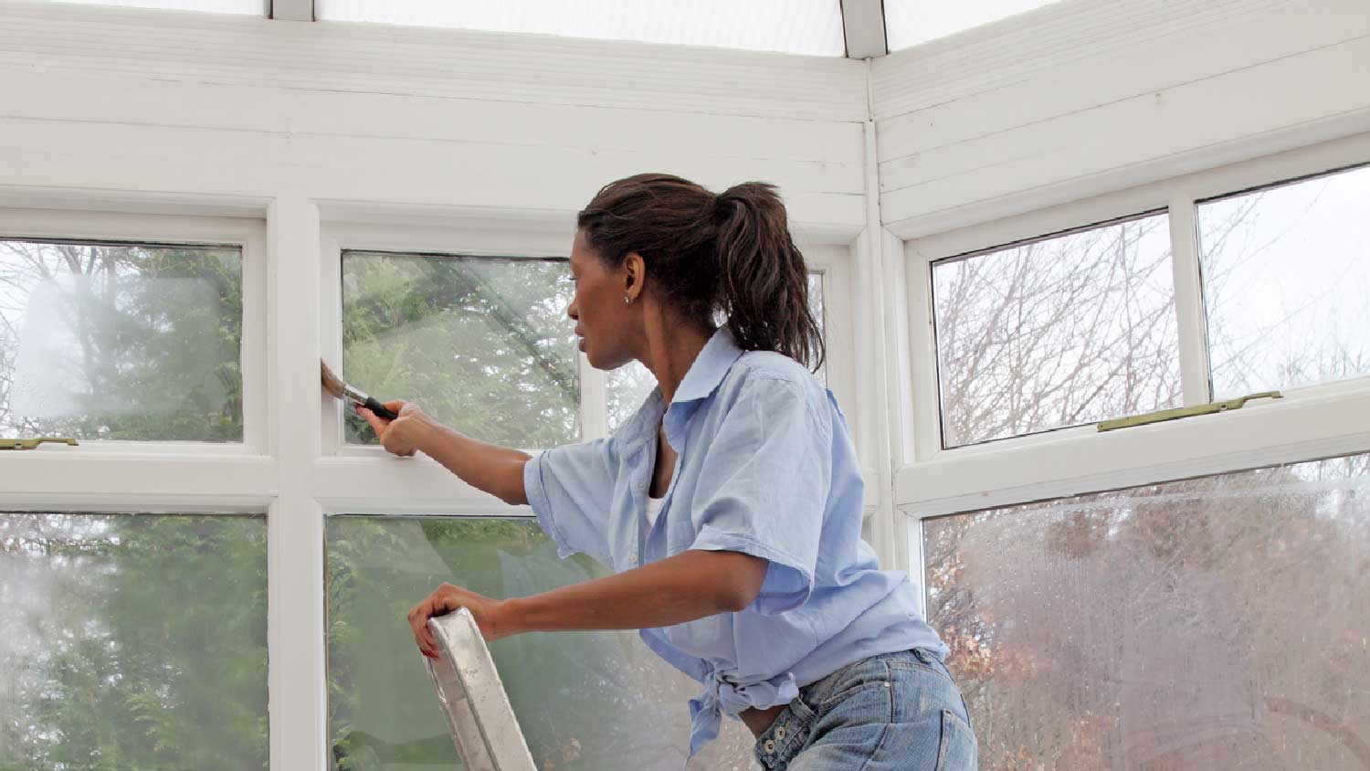 A woman painting a sunroom