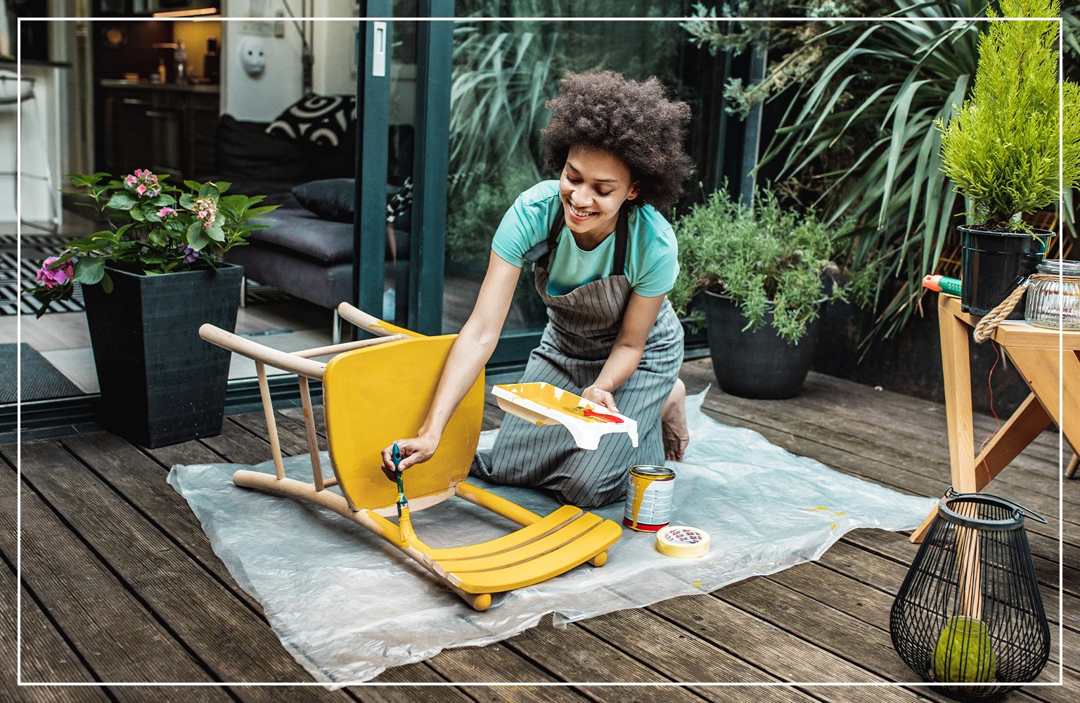 woman painting yellow chair in garden