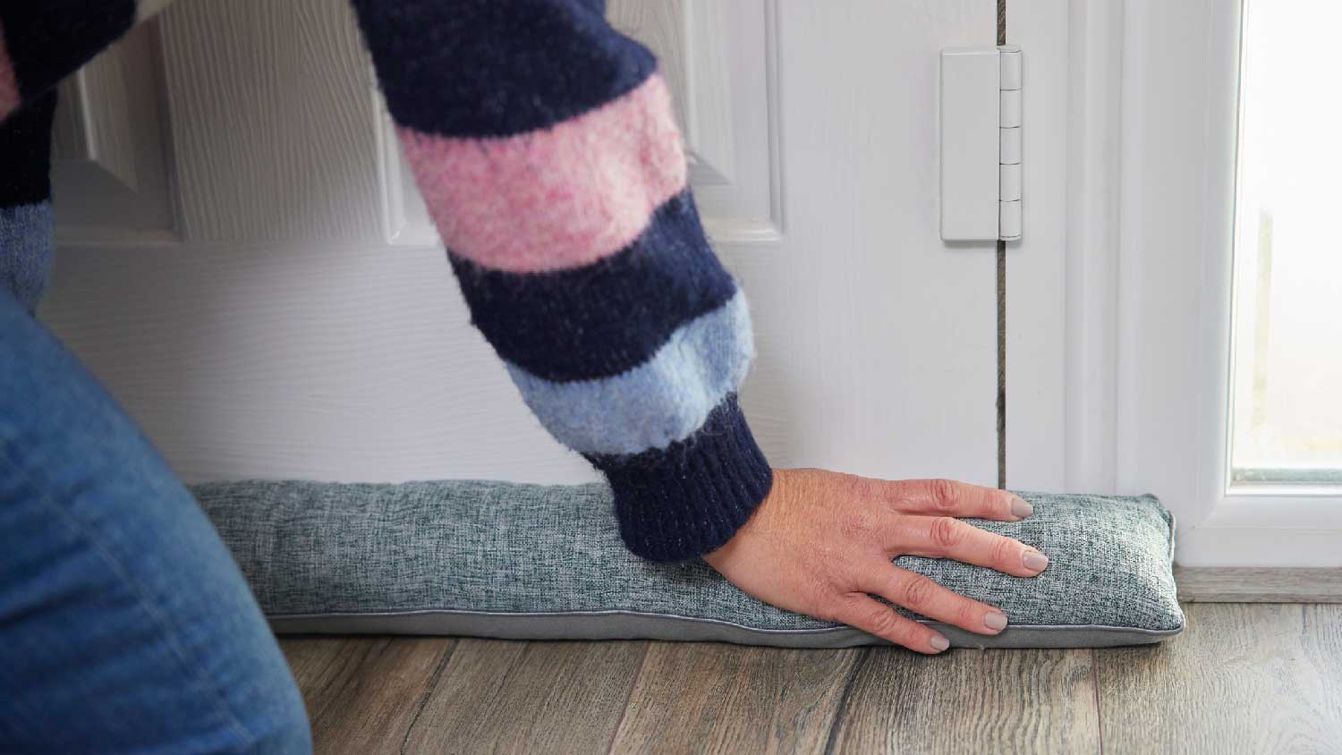 A woman placing a draft stopper at a door