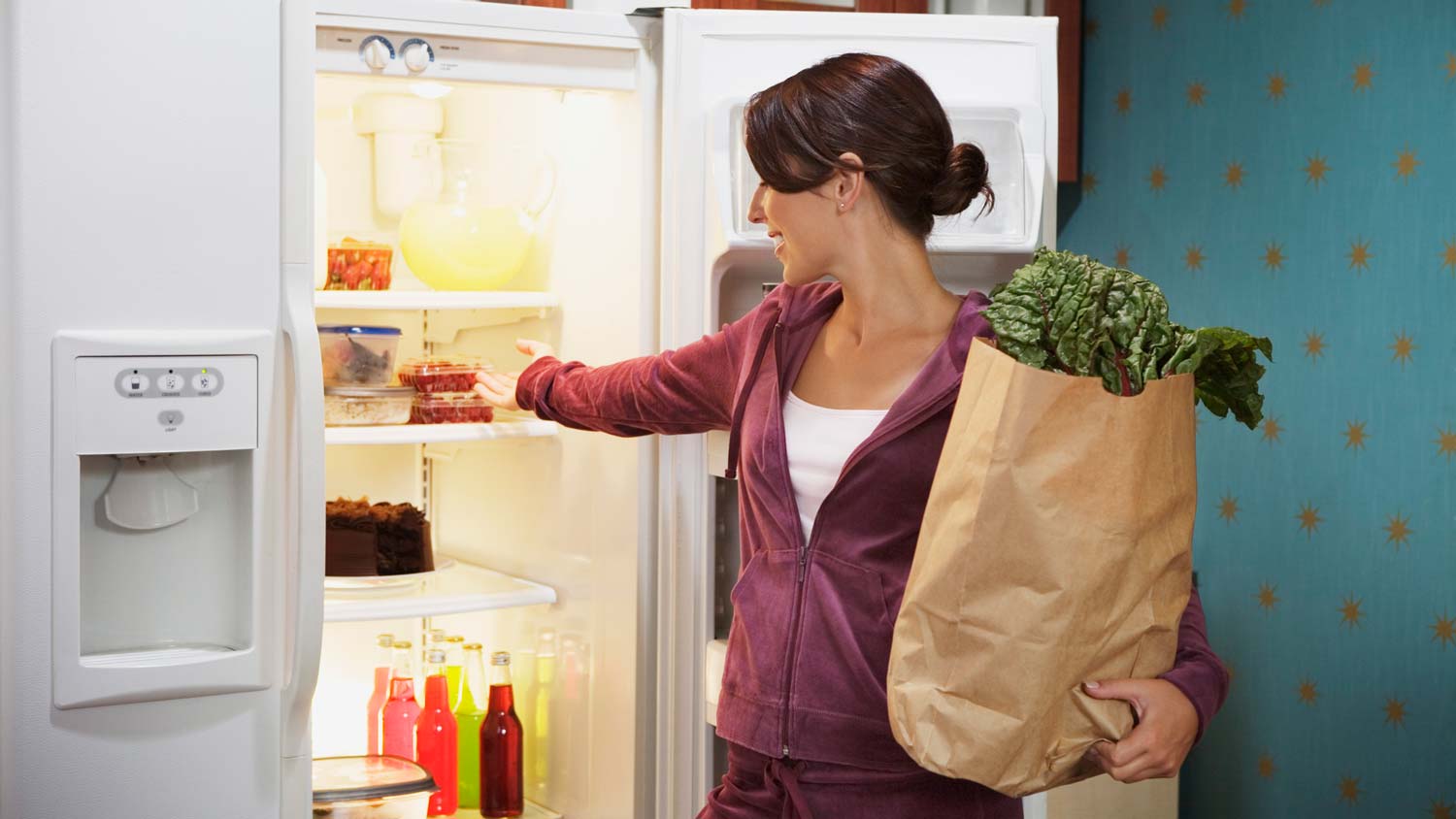 A woman placing groceries inside a fridge